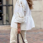 White blouse with a V-neckline and openwork sleeves